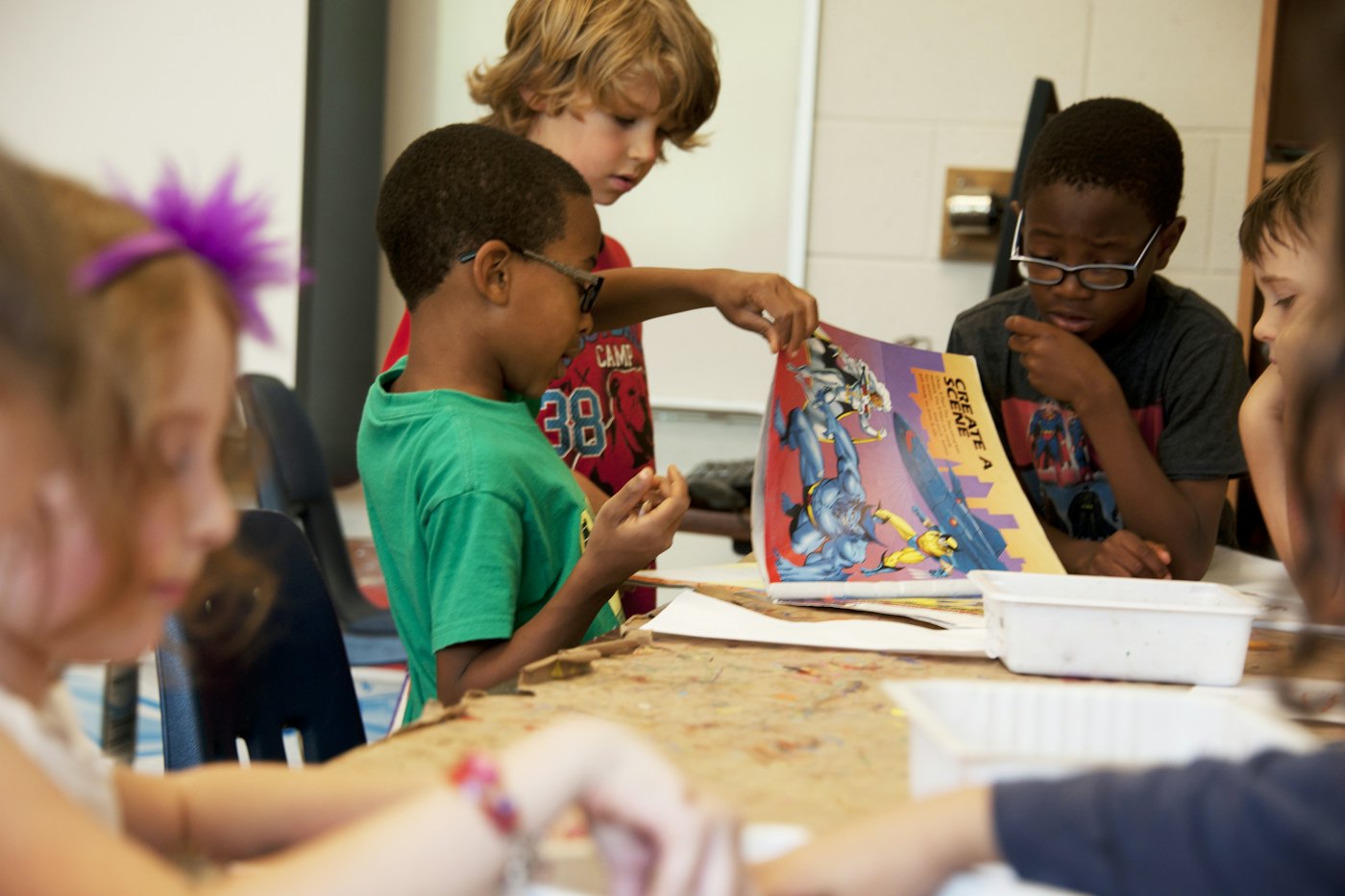 Kids gather around a table during a camp craft activity, building a sticker scene