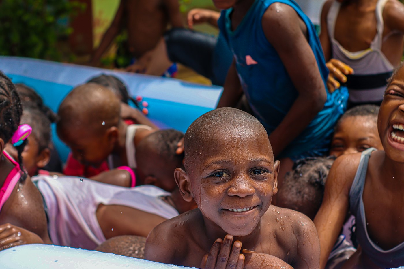 A grinning boy and his friends splash in an inflatable pool on a summer day